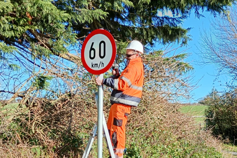 Man in Orange erecting speed sign