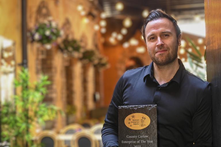 Man leaning against wall with award