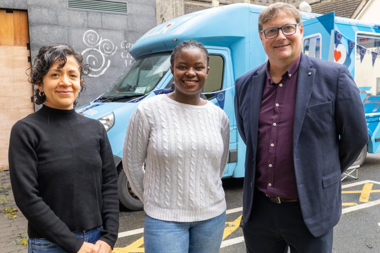 3 People standing in front of a blue van