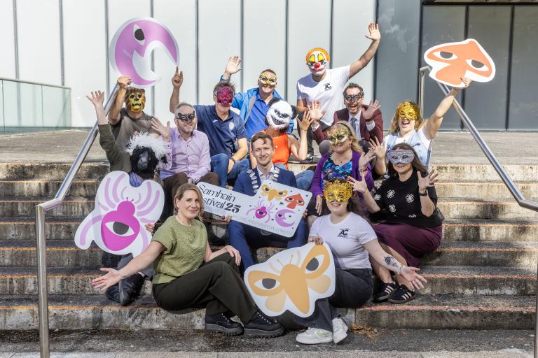 Group sitting on steps with masks in hand