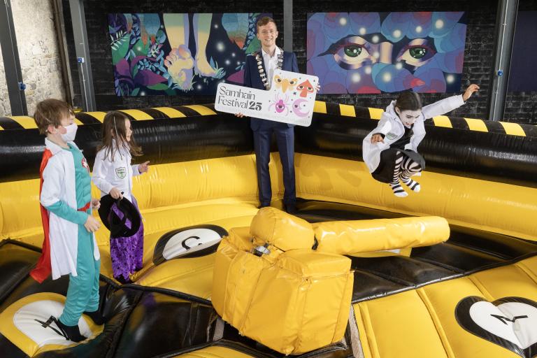Children in costume and man holding a sign on a bouncy castle