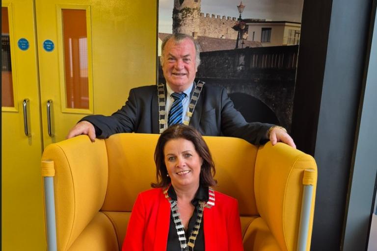 woman sitting in yellow chair and man standing behind chair