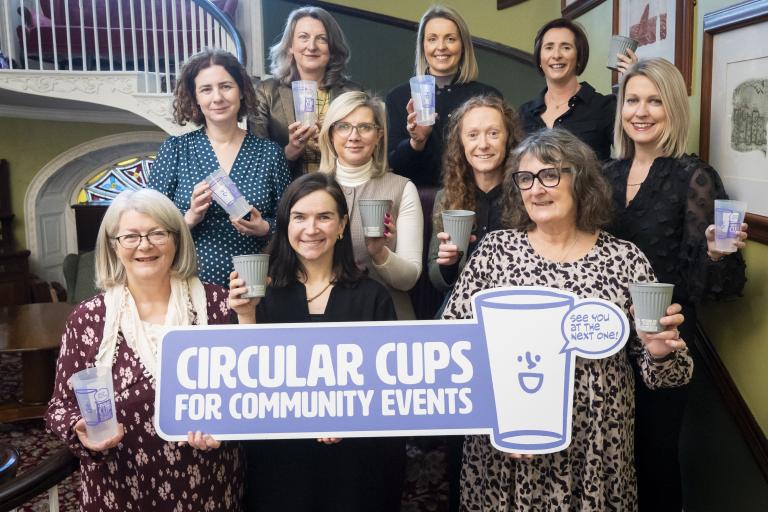 Women standing on stairs with cups