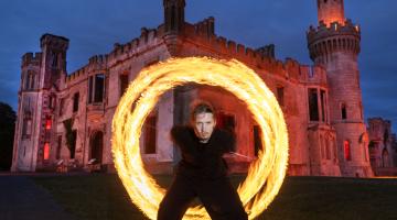 Man with ring of fire in front of old castle