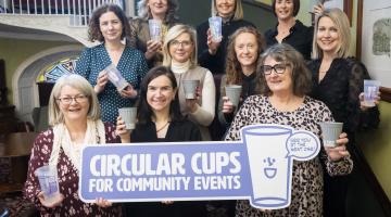 Women standing on stairs with cups