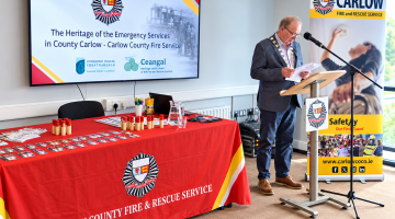 Man at podium with fire service posters